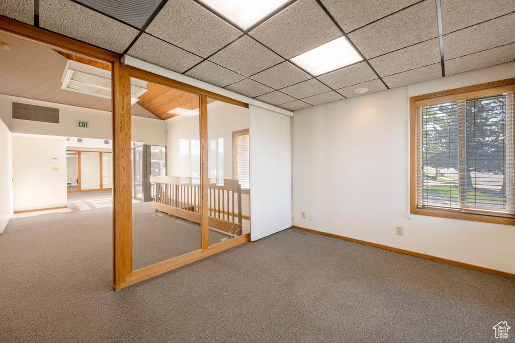 Carpeted empty room featuring lofted ceiling and a paneled ceiling
