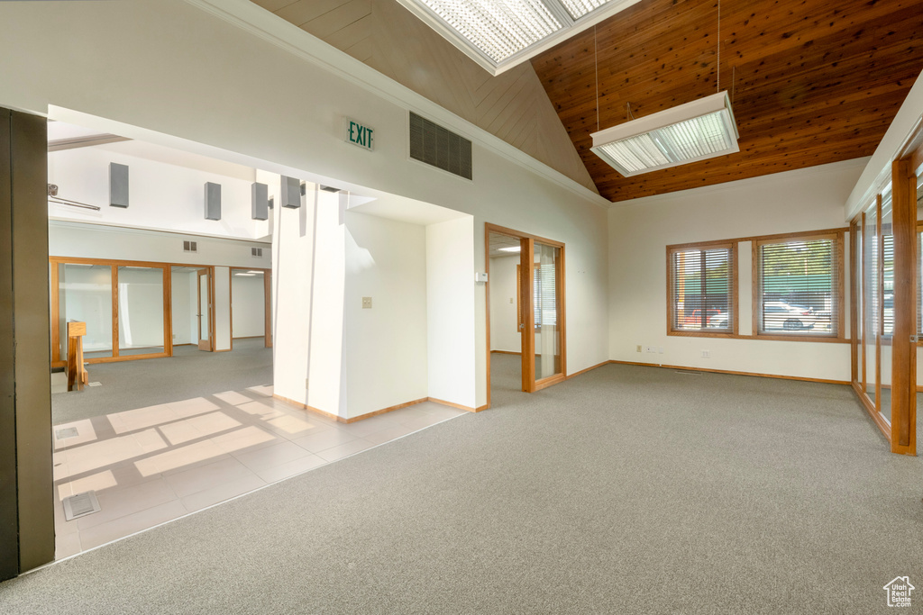 Empty room with high vaulted ceiling, light colored carpet, and wooden ceiling