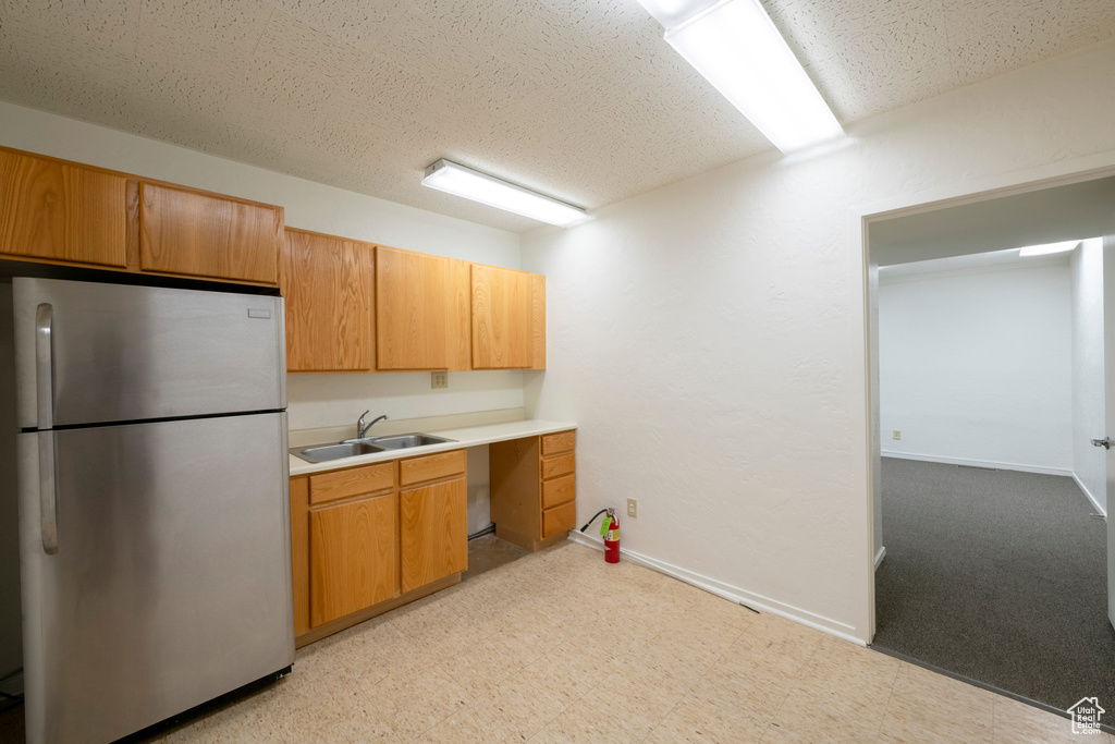 Kitchen featuring stainless steel fridge, light colored carpet, a textured ceiling, and sink