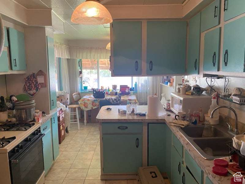 Kitchen with white appliances, light tile patterned floors, kitchen peninsula, and sink