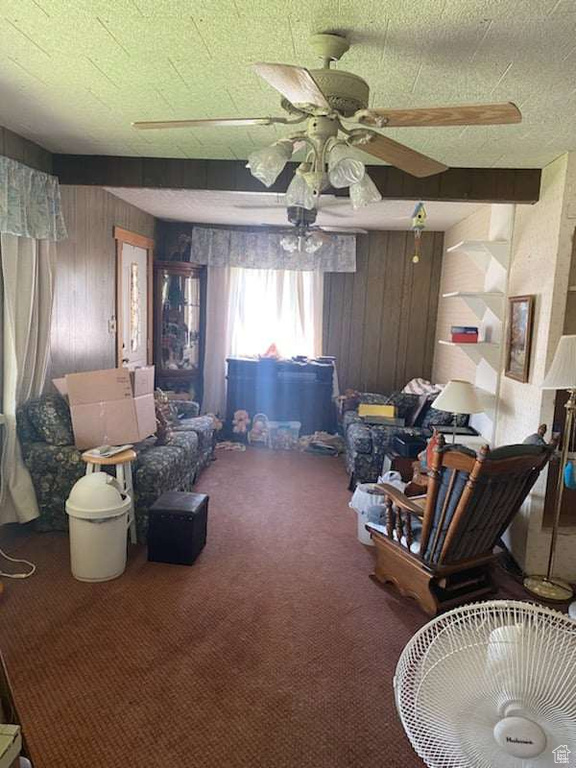 Living room featuring a textured ceiling, ceiling fan, carpet floors, and wooden walls