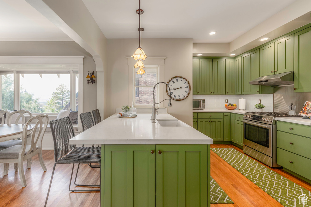 Kitchen with appliances with stainless steel finishes, a center island with sink, green cabinets, and sink