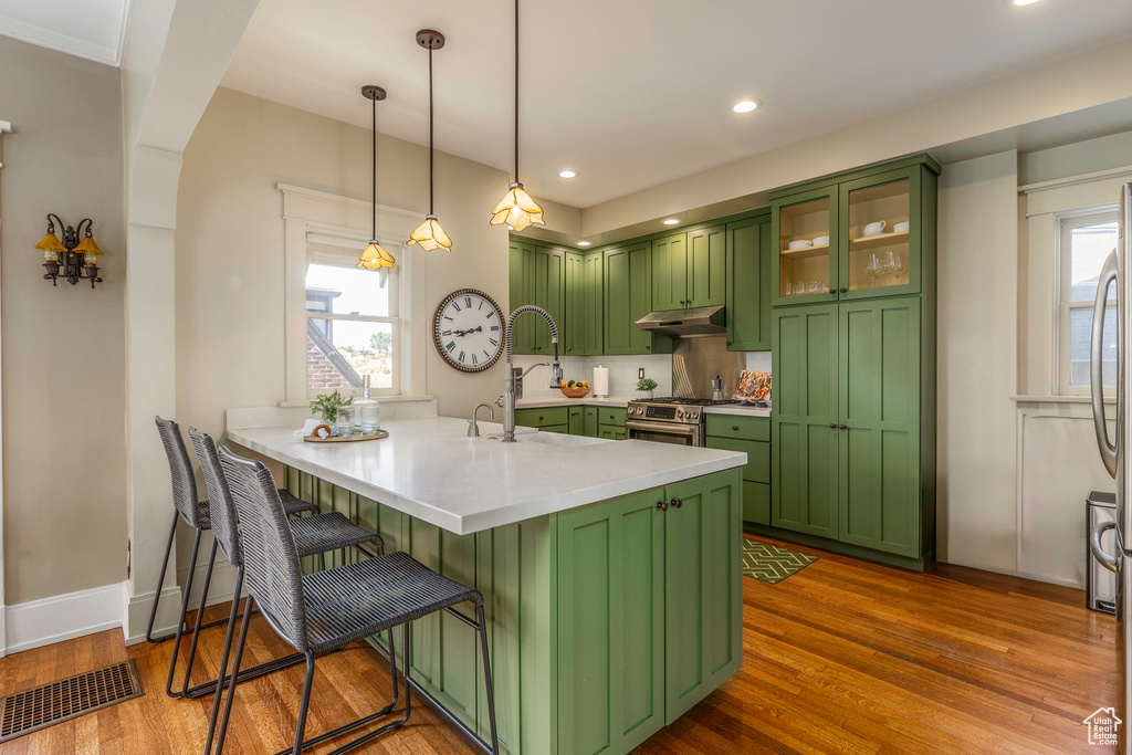 Kitchen featuring green cabinetry, a healthy amount of sunlight, and wood-type flooring