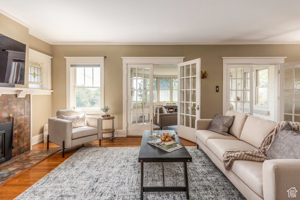 Living room with ornamental molding, a fireplace, hardwood / wood-style floors, and french doors