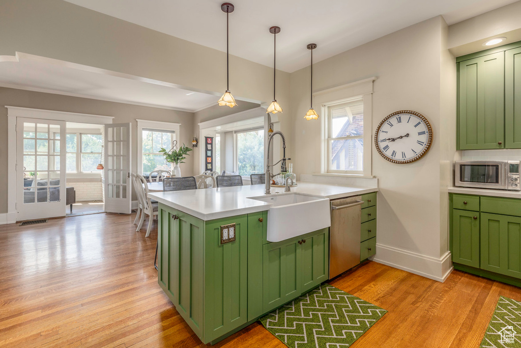 Kitchen featuring stainless steel appliances, green cabinets, light hardwood / wood-style flooring, and a wealth of natural light