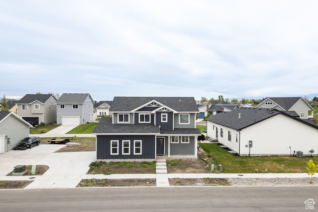 View of front of house with concrete driveway, a shingled roof, central AC unit, and a residential view