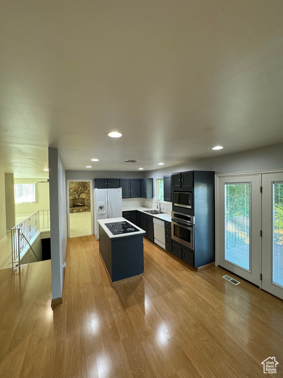 Kitchen with a kitchen island, sink, stainless steel appliances, and light wood-type flooring