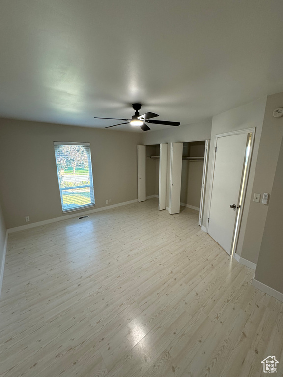 Unfurnished bedroom with ceiling fan, multiple closets, and light hardwood / wood-style floors