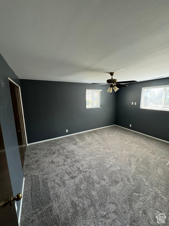 Carpeted spare room with ceiling fan and a textured ceiling