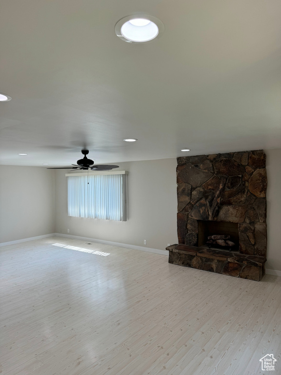 Living room with light hardwood / wood-style floors, ceiling fan, and a fireplace