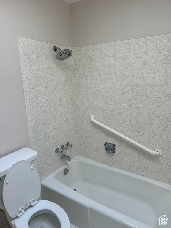 Bathroom featuring tiled shower / bath combo and toilet