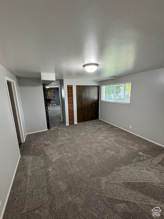 Unfurnished bedroom with dark carpet