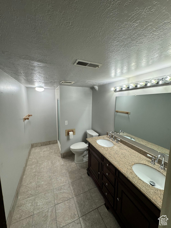 Bathroom featuring toilet, a textured ceiling, and vanity