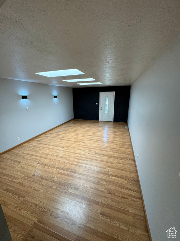 Interior space featuring a skylight, light hardwood / wood-style floors, and a textured ceiling