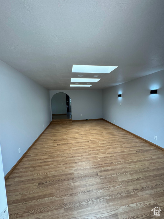 Additional living space featuring a skylight and light hardwood / wood-style flooring