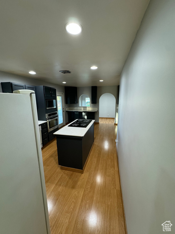 Kitchen featuring stainless steel appliances, a kitchen island, and light hardwood / wood-style flooring