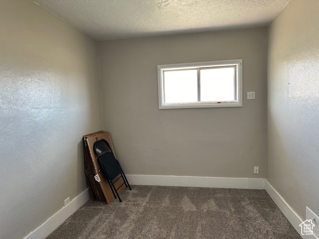 Spare room featuring dark colored carpet and a textured ceiling