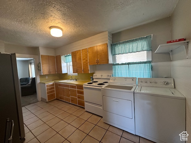 Kitchen featuring separate washer and dryer, stainless steel fridge, a textured ceiling, sink, and white electric range oven