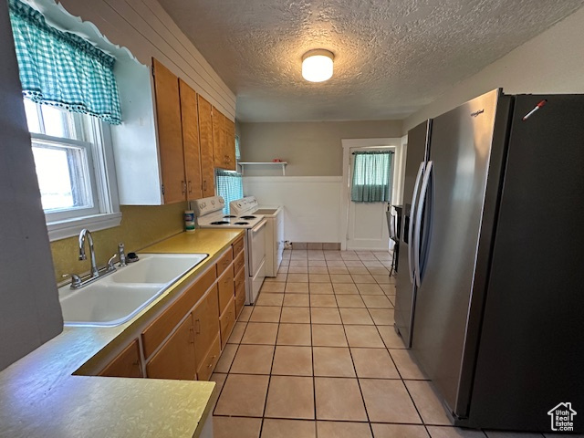 Kitchen featuring a textured ceiling, sink, stainless steel fridge, separate washer and dryer, and white electric range oven