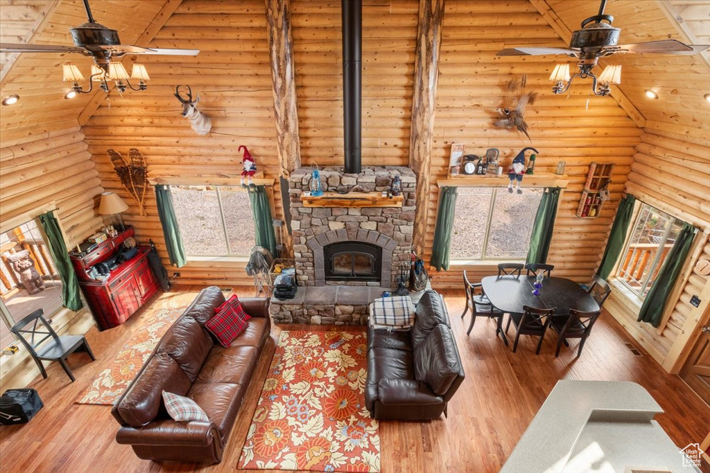 Living room featuring a fireplace, hardwood / wood-style flooring, ceiling fan, and rustic walls