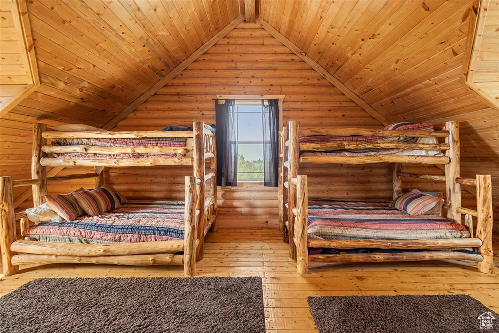 Bedroom with light wood-type flooring, lofted ceiling, log walls, and wooden ceiling