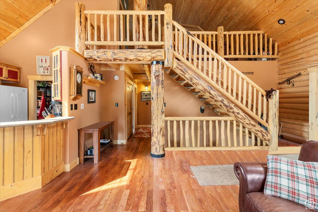 Living room with wood ceiling, high vaulted ceiling, wood-type flooring, and rustic walls