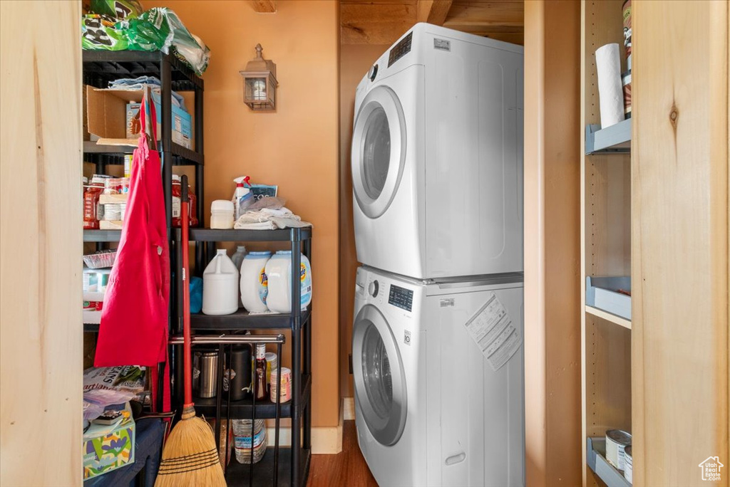 Laundry area featuring wood-type flooring and stacked washer / dryer