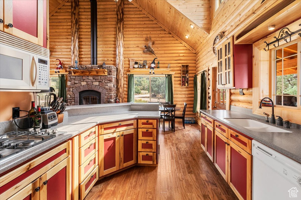 Kitchen with log walls, white appliances, hardwood / wood-style floors, sink, and high vaulted ceiling