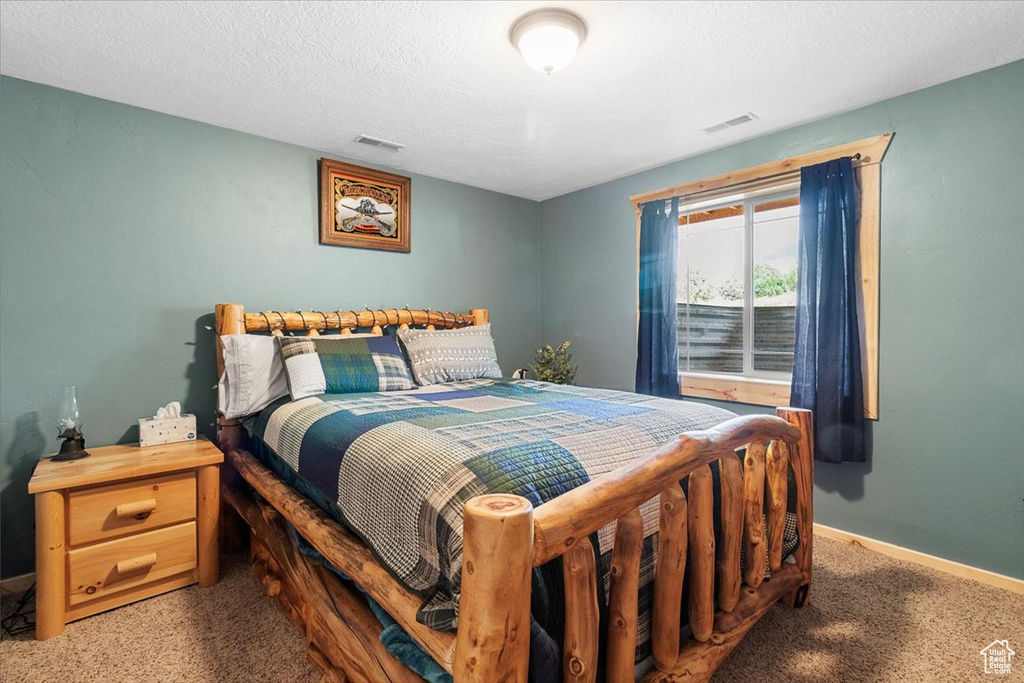 Bedroom with a textured ceiling and carpet floors