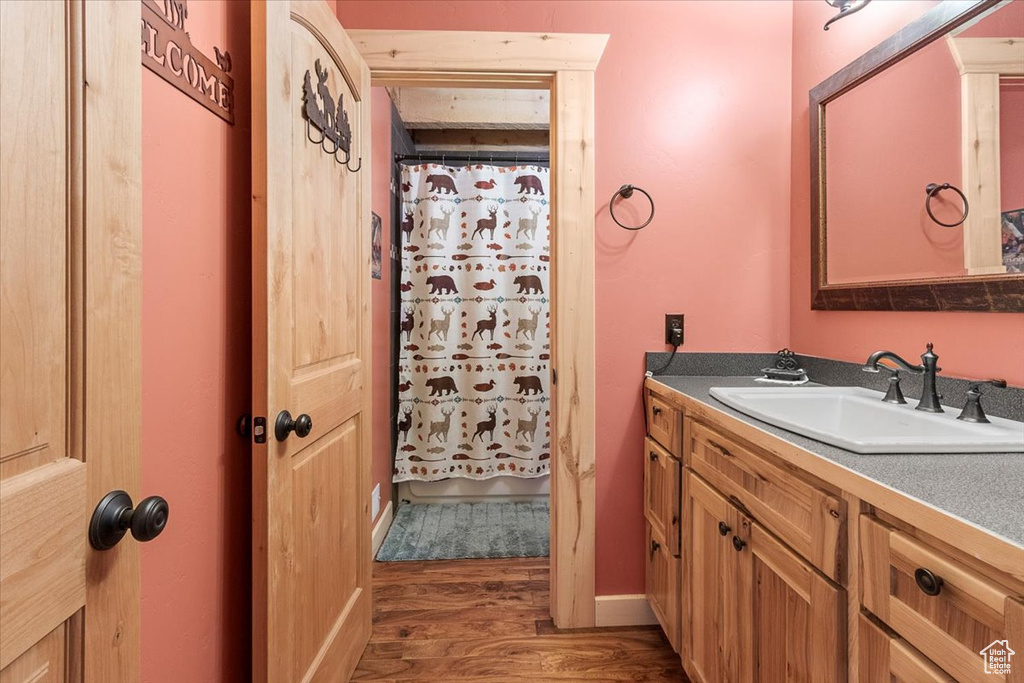 Bathroom with vanity, a shower with shower curtain, and hardwood / wood-style flooring