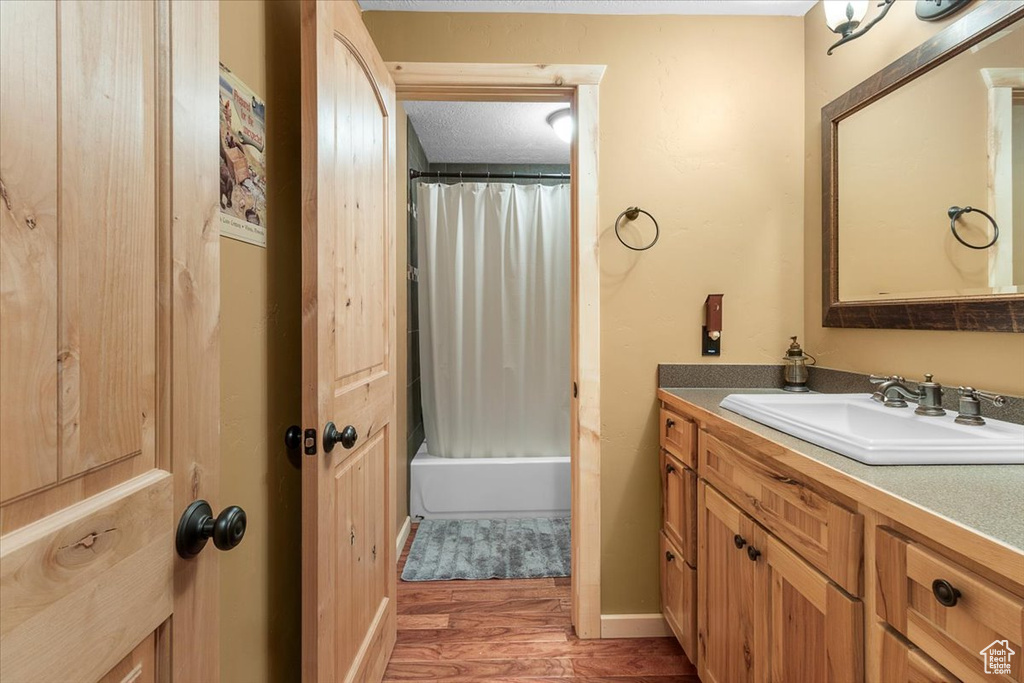 Bathroom with shower / bath combination with curtain, wood-type flooring, a textured ceiling, and vanity