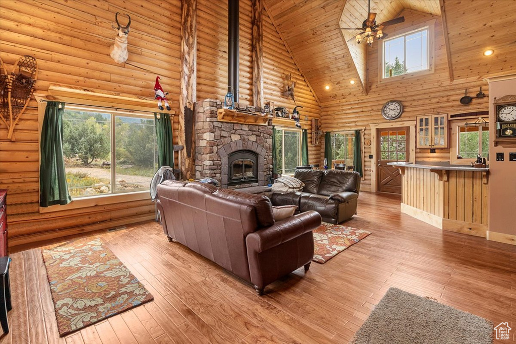 Living room featuring a fireplace, high vaulted ceiling, ceiling fan, wooden ceiling, and light hardwood / wood-style floors