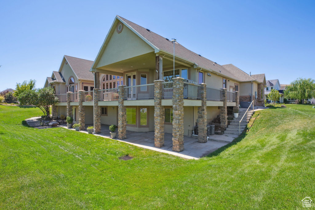 Rear view of property with a lawn and a patio area