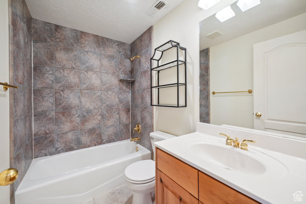 Full bathroom featuring vanity, tile patterned flooring, toilet, a skylight, and tiled shower / bath combo