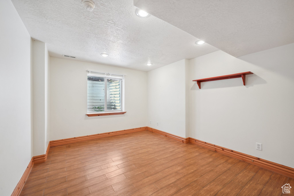 Spare room with light wood-type flooring and a textured ceiling