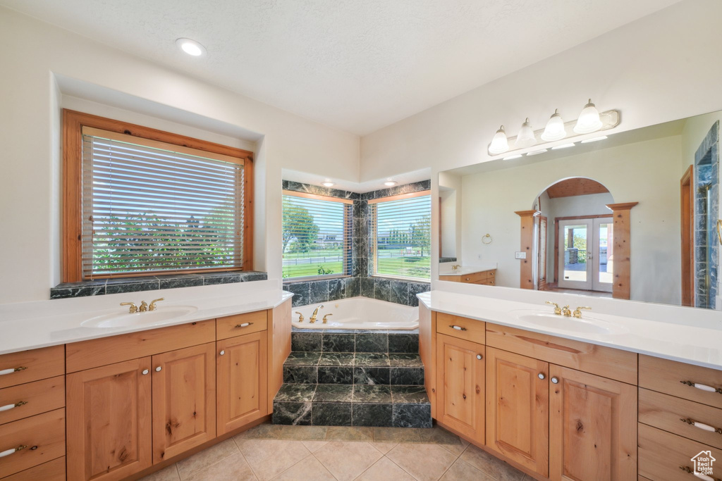 Bathroom featuring vanity, tiled tub, tile patterned floors, and french doors