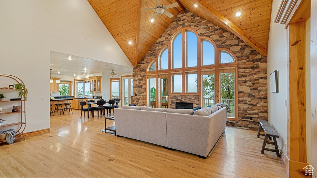 Living room featuring ceiling fan, light wood-type flooring, high vaulted ceiling, and a fireplace