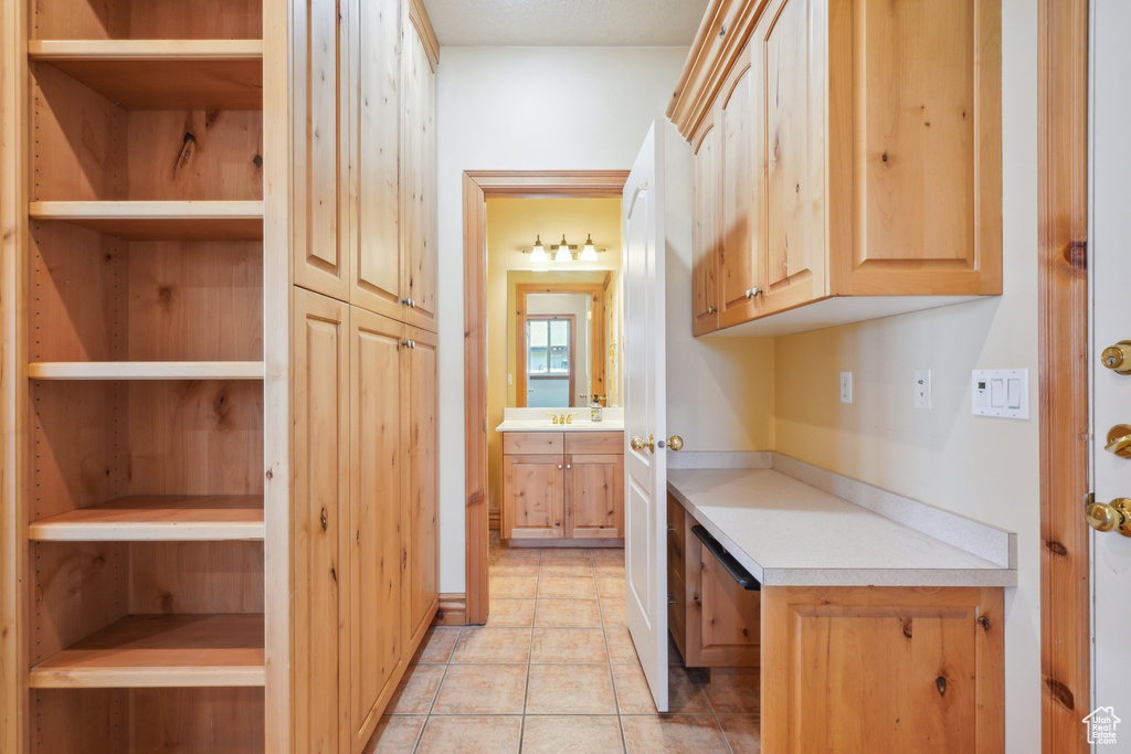 Kitchen with light tile patterned floors, sink, and light brown cabinets