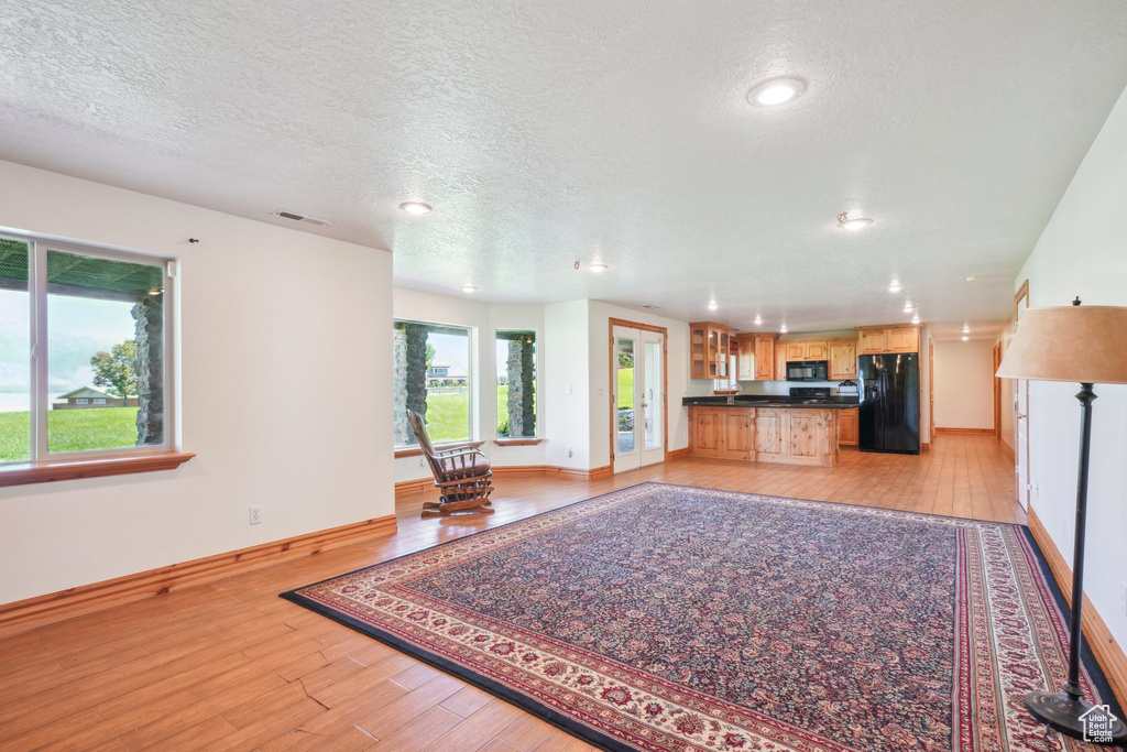 Unfurnished living room with a textured ceiling and light hardwood / wood-style flooring