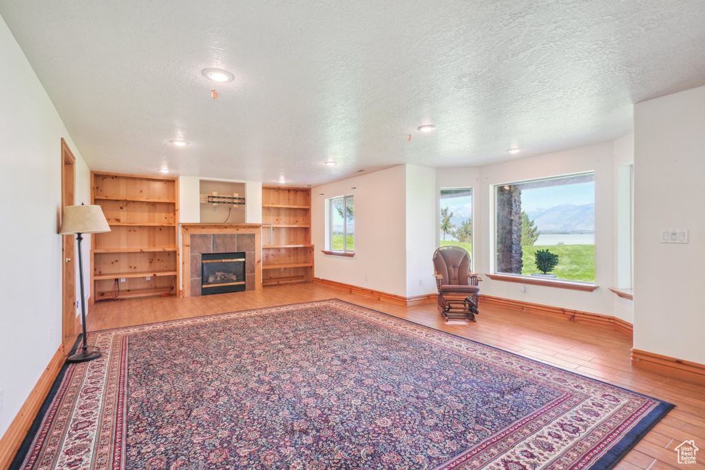 Unfurnished living room with a textured ceiling, hardwood / wood-style floors, and a fireplace