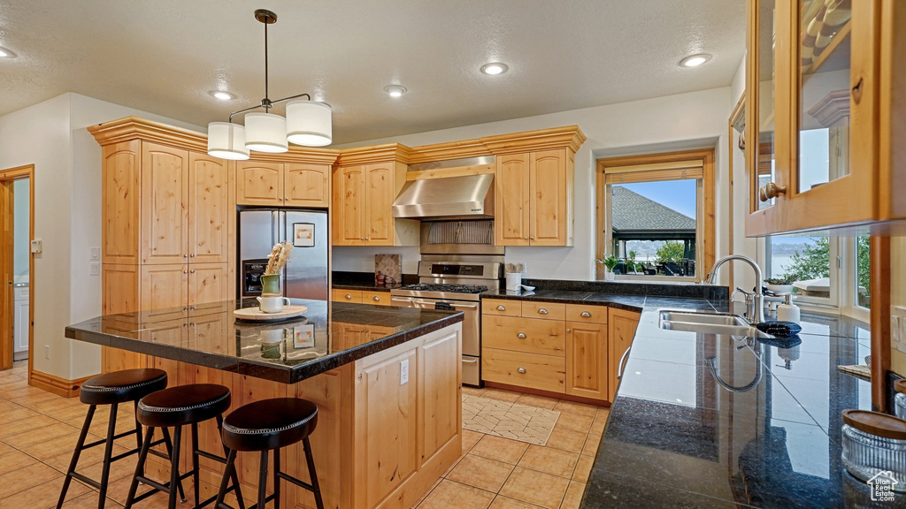 Kitchen featuring exhaust hood, sink, a center island, appliances with stainless steel finishes, and light brown cabinets