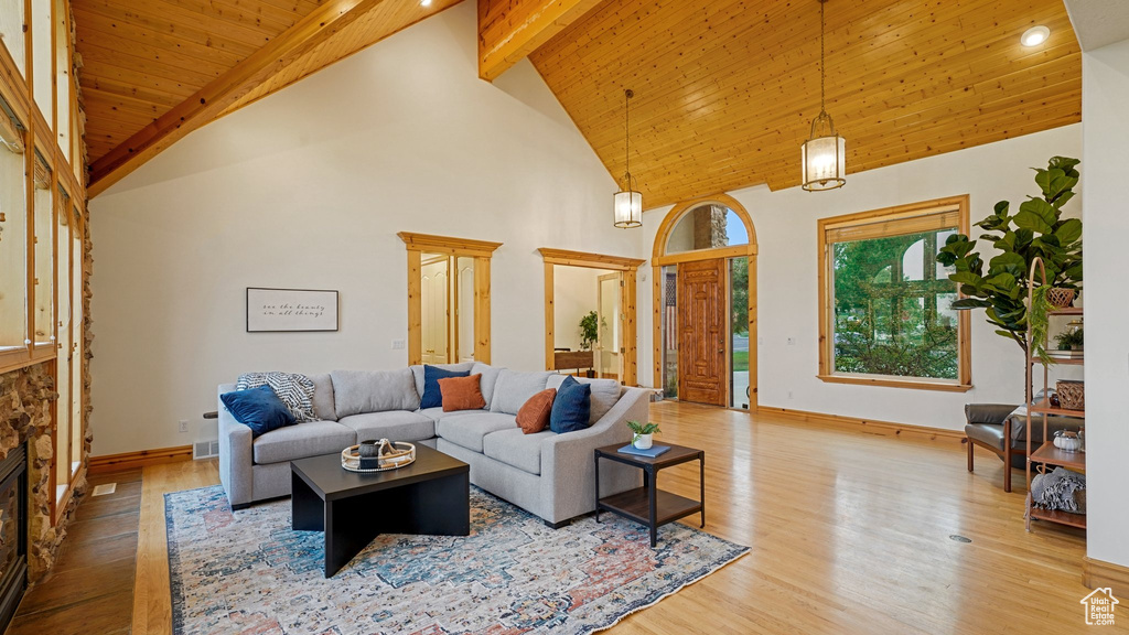 Living room featuring light hardwood / wood-style flooring, beamed ceiling, high vaulted ceiling, and a fireplace