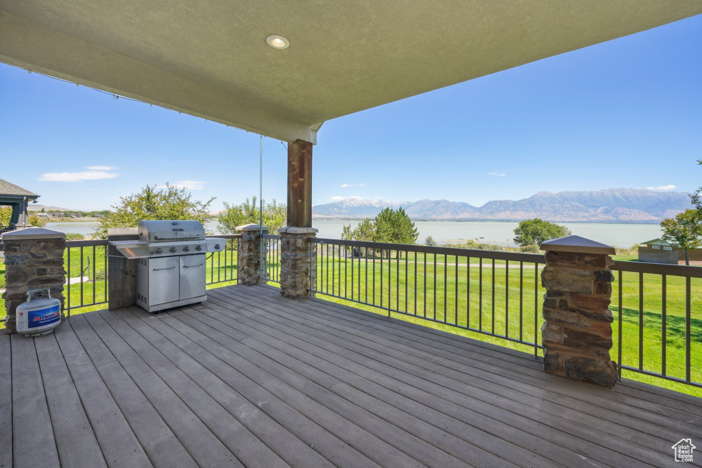 Wooden deck featuring a yard, a water and mountain view, and a grill