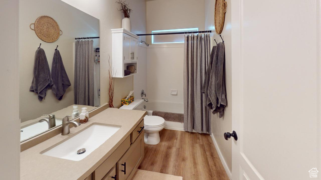 Full bathroom featuring shower / bath combination with curtain, toilet, wood-type flooring, and vanity