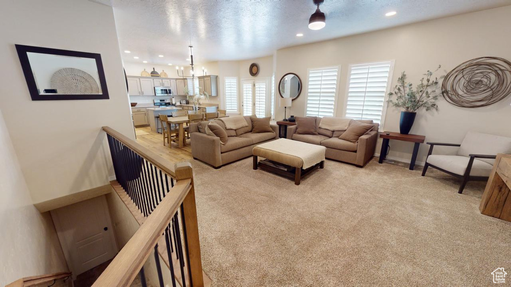 Carpeted living room featuring a textured ceiling and an inviting chandelier