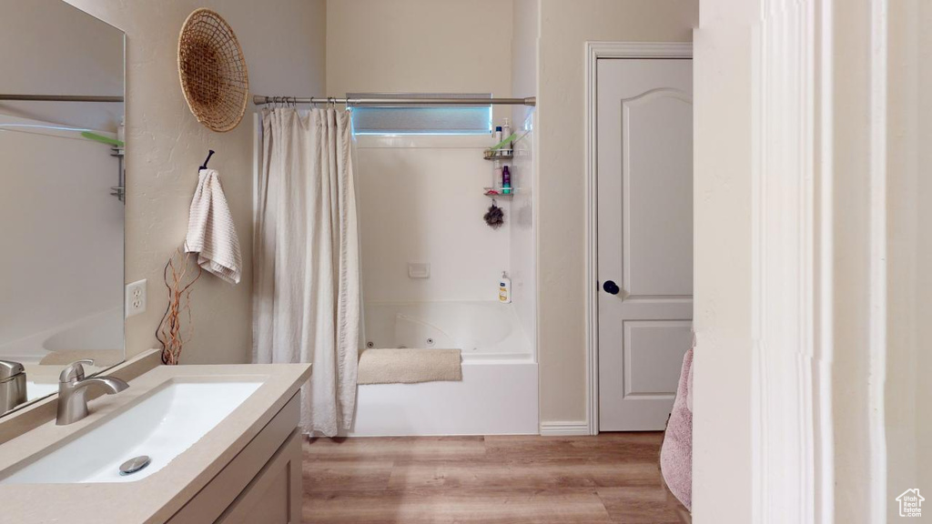 Bathroom featuring vanity, hardwood / wood-style flooring, and shower / bathtub combination with curtain