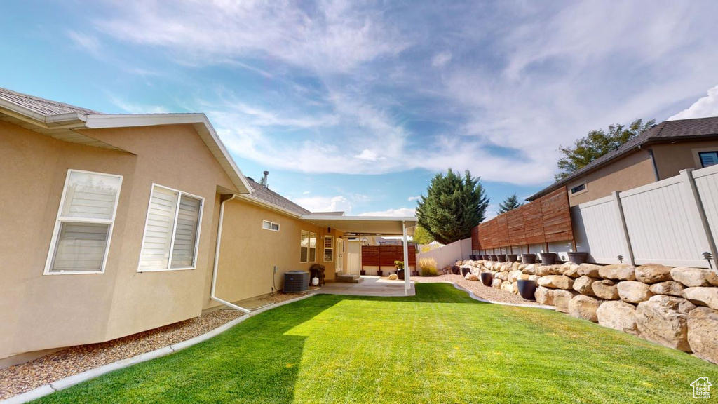 View of yard featuring central AC unit, ceiling fan, and a patio