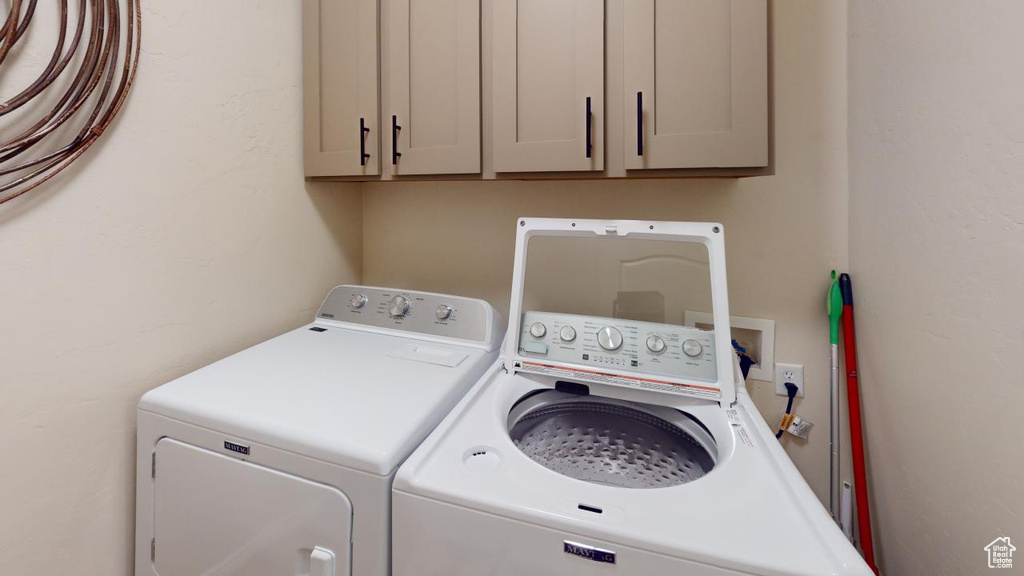 Washroom featuring independent washer and dryer and cabinets