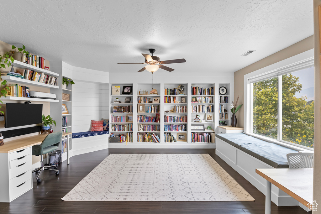 Office with a textured ceiling, dark wood-type flooring, and ceiling fan