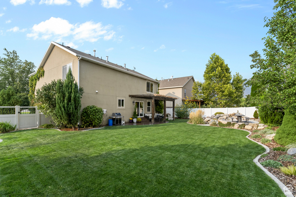 Back of property with a pergola, a lawn, and a patio area